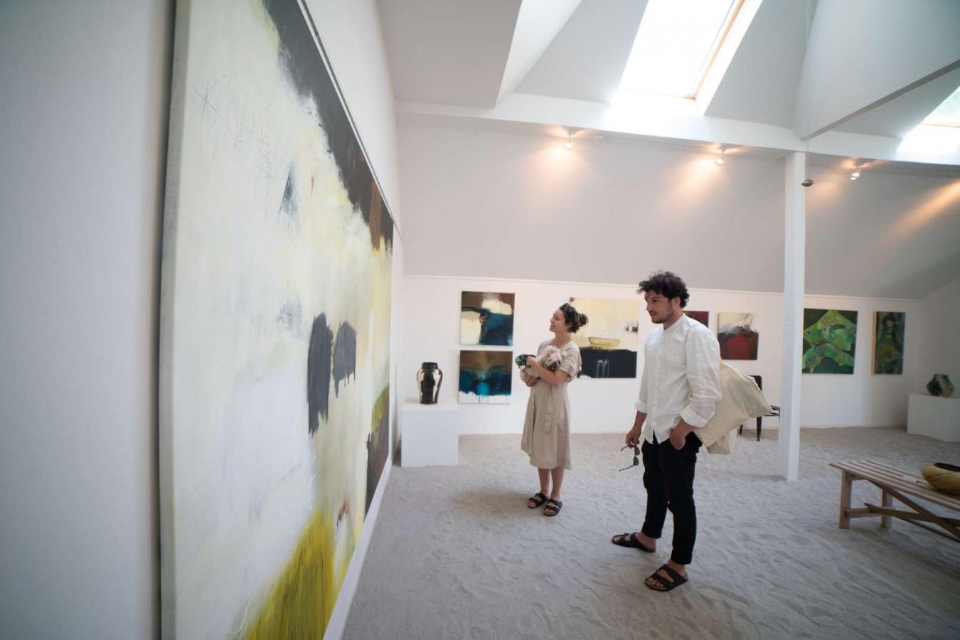 En kvinde og en mand nyder kunsten på Galleri Kirkesvinget på Hjarnø i Destination Kystlandet