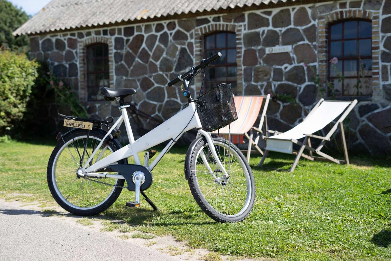 Udlejningscykel parkeret foran Vestergaards Mølleri med to solstole i baggrunden
