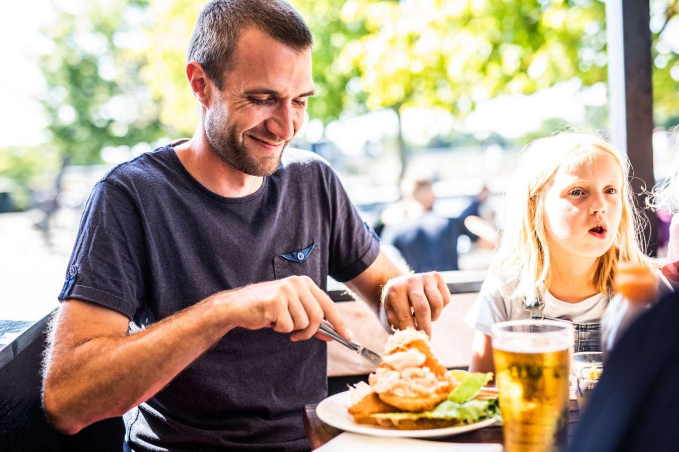 Man eating at Norsminde Fiskehus in Destination Coastal Land with the family