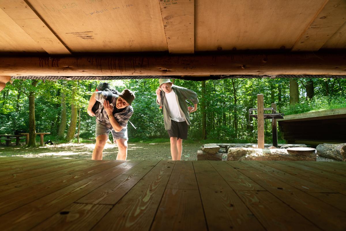 Zwei Freunde schauen in der Urlaubsregion Küstenland in einen Shelter hinein