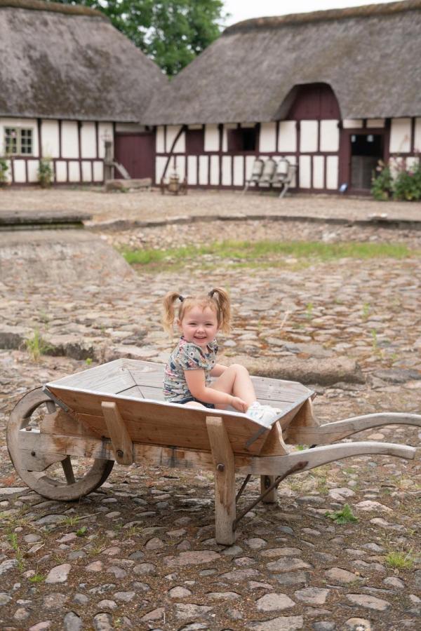 brosten på gårdsplads med barn i trillebøre og hvid gård i baggrunden