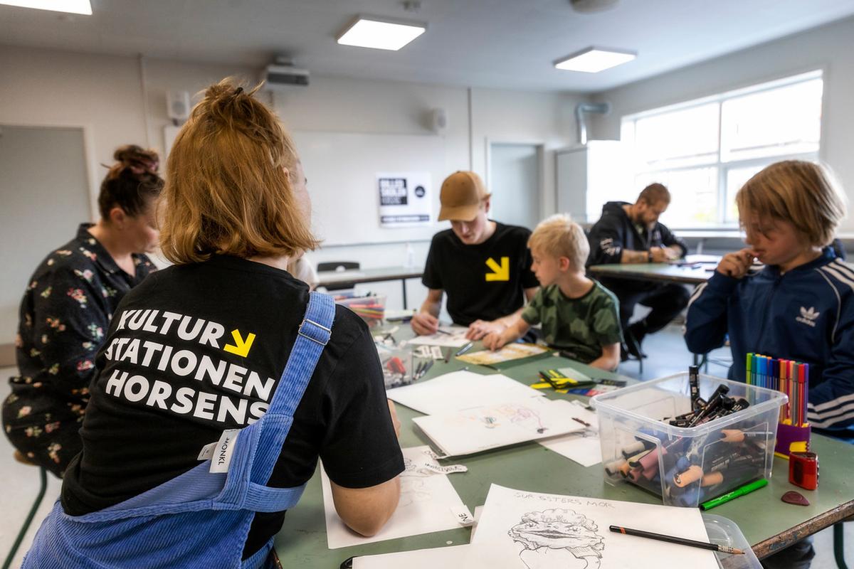 Børn og familier sidder ved et bord og tegner på Kulturstationen i Horsens, Destination Kystlandet