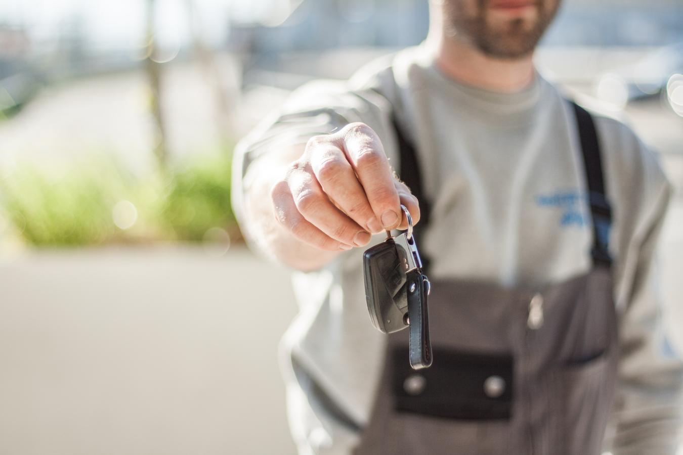 A man holding out car keys at car hire company