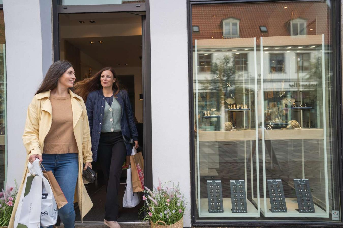 Two women with bags in their hands on their way out of a shop in Horsens
