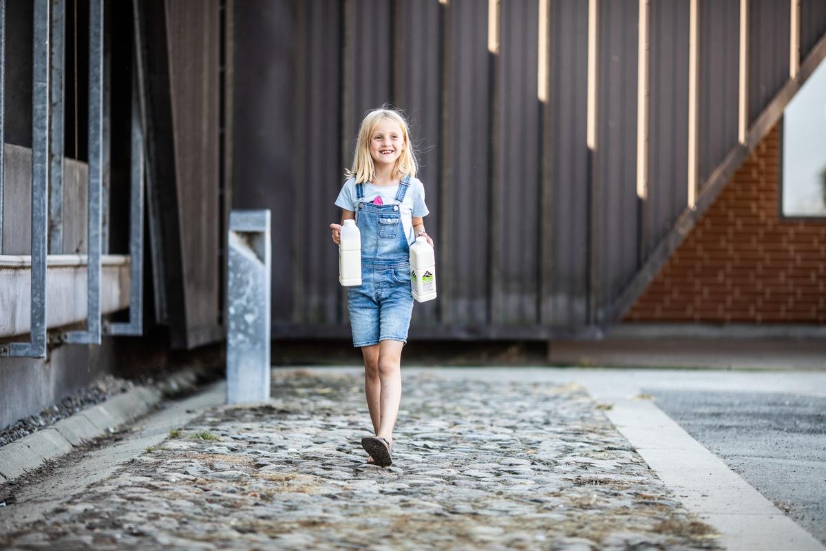 Lille pige bærer på to liter mælk ved Vejlskovgaard mælketapperi i Destination Kystlandet