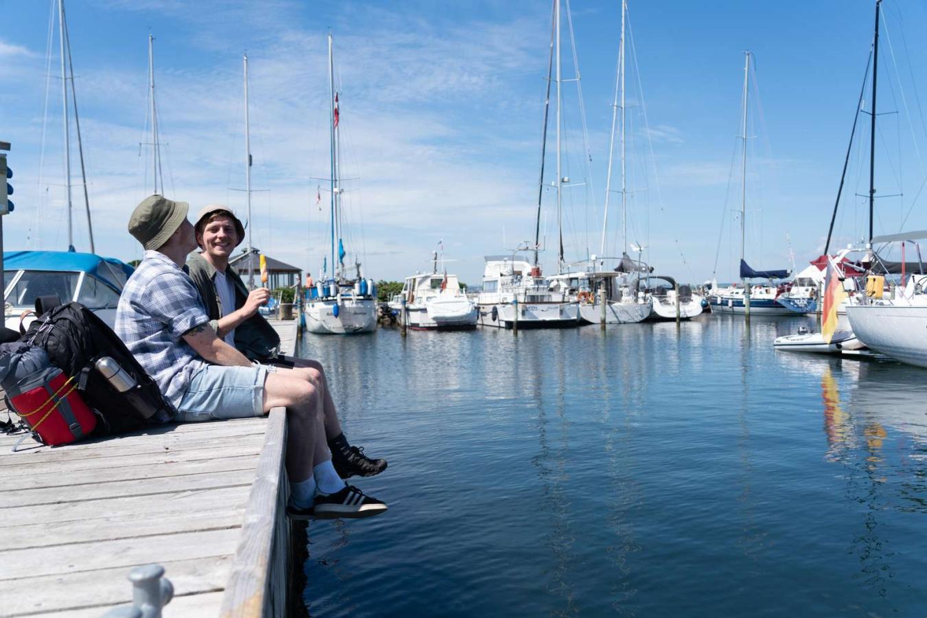 Zwei Wanderer essen Eis auf der Mole im Jachthafen von Snaptun