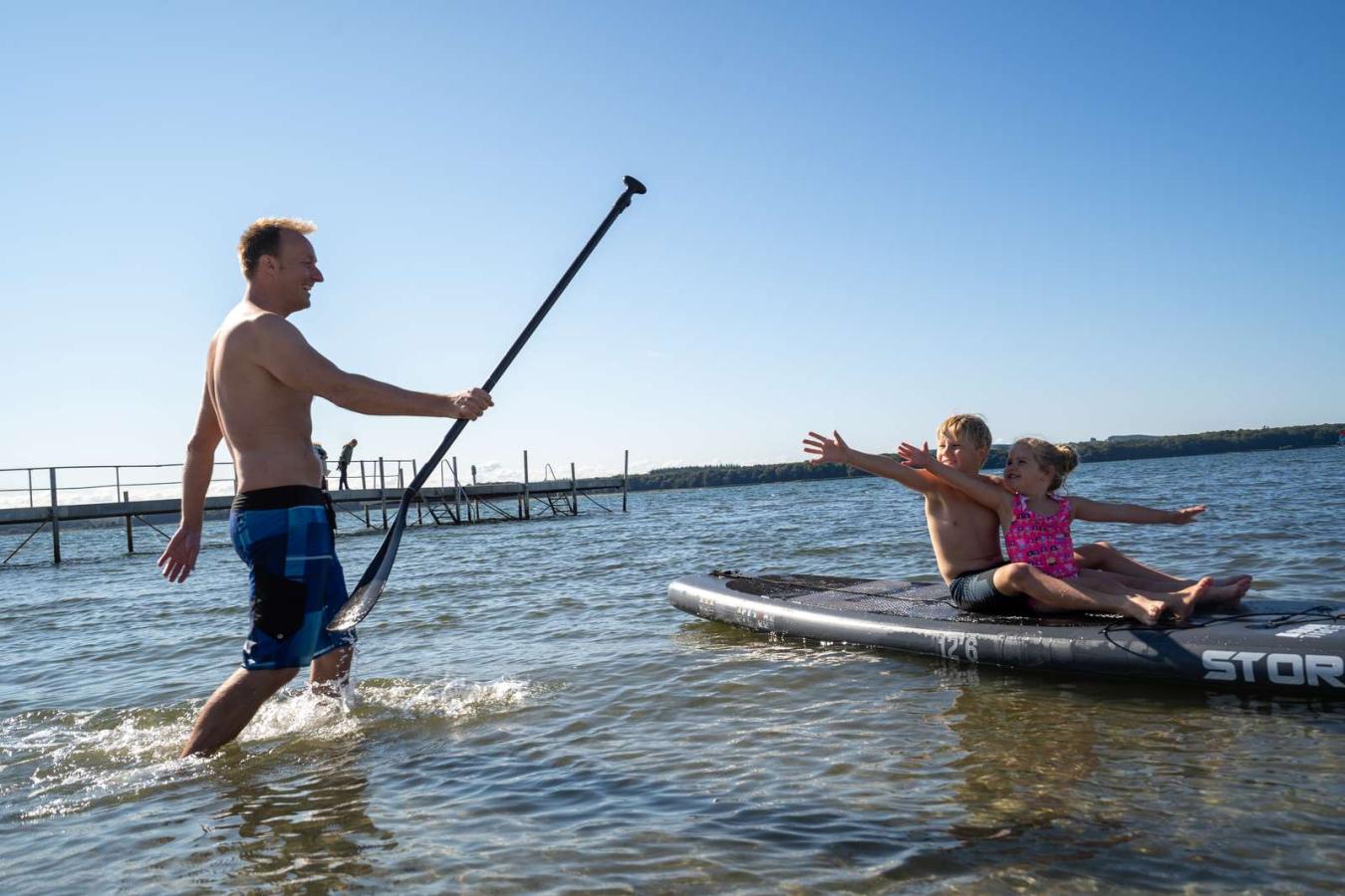 Children sitting on an SUP-board at Husodde Beach