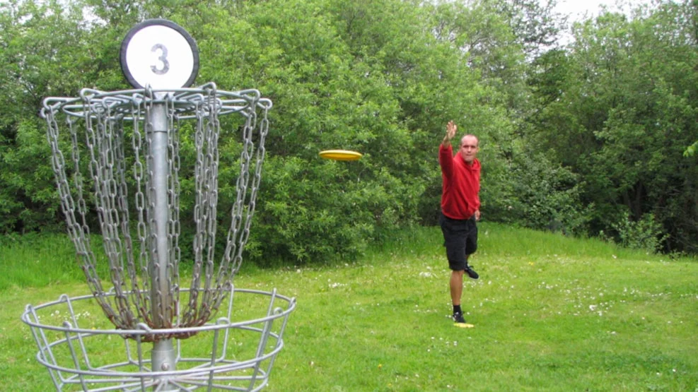 Mand spiller disc-golf med frisbee i park 