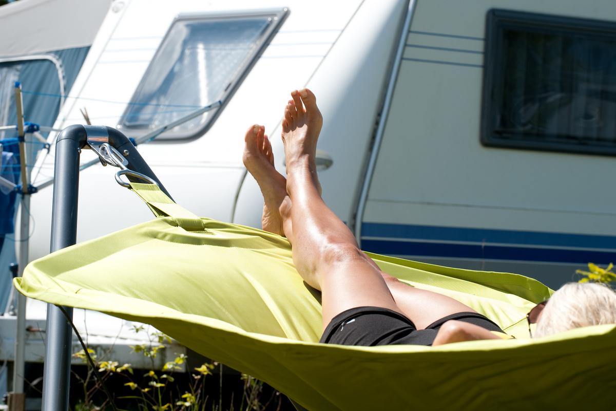 En kvinde ligger i en liggestol ved en campingvogn hos Hou Strandcamping