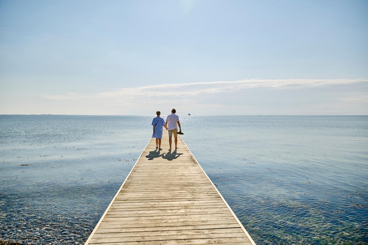 Et par går på badebroen på Hølken Strand