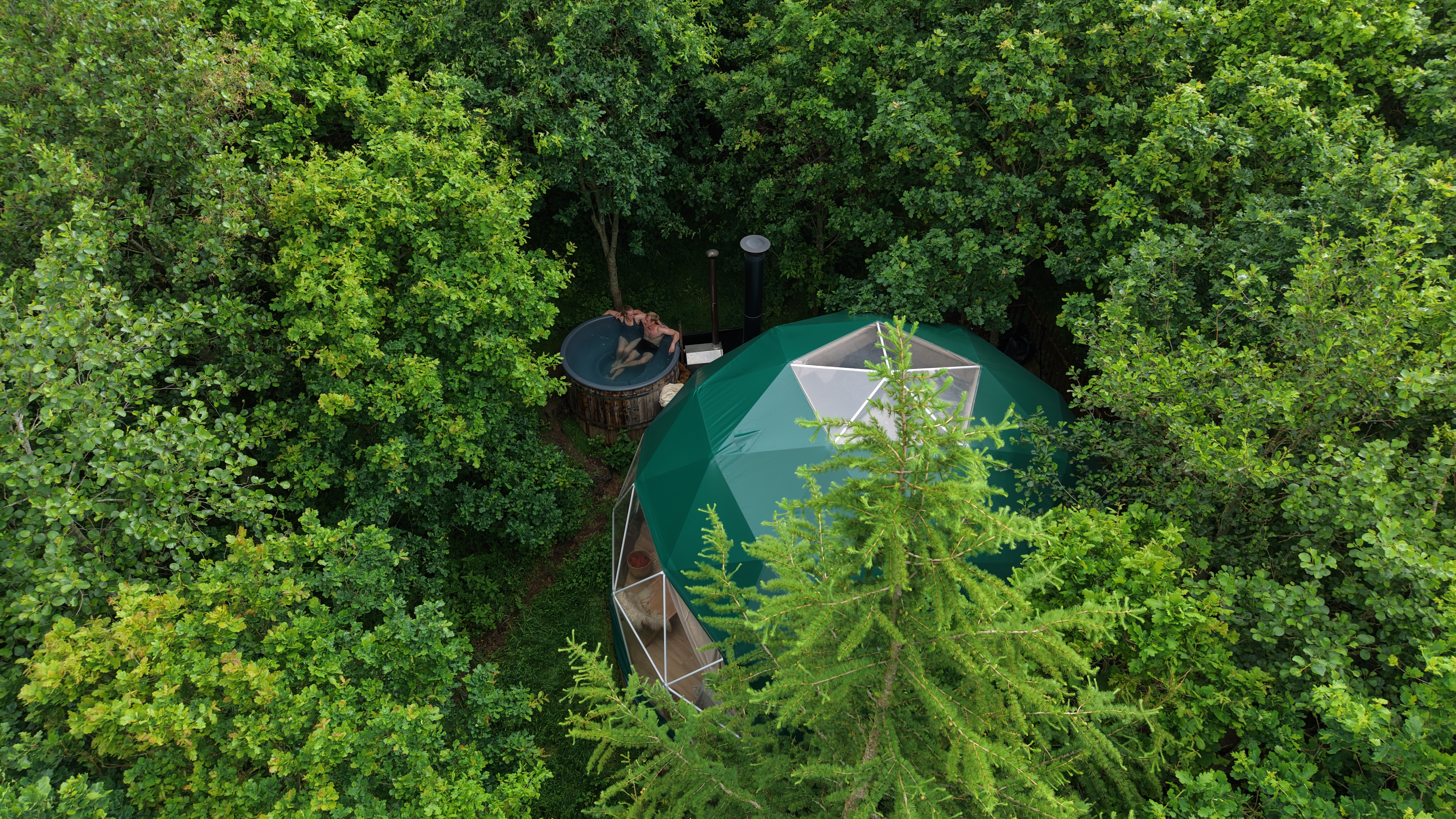 Dronefoto af glamping domen Bøgebjerg med et par i vildmarksbadet