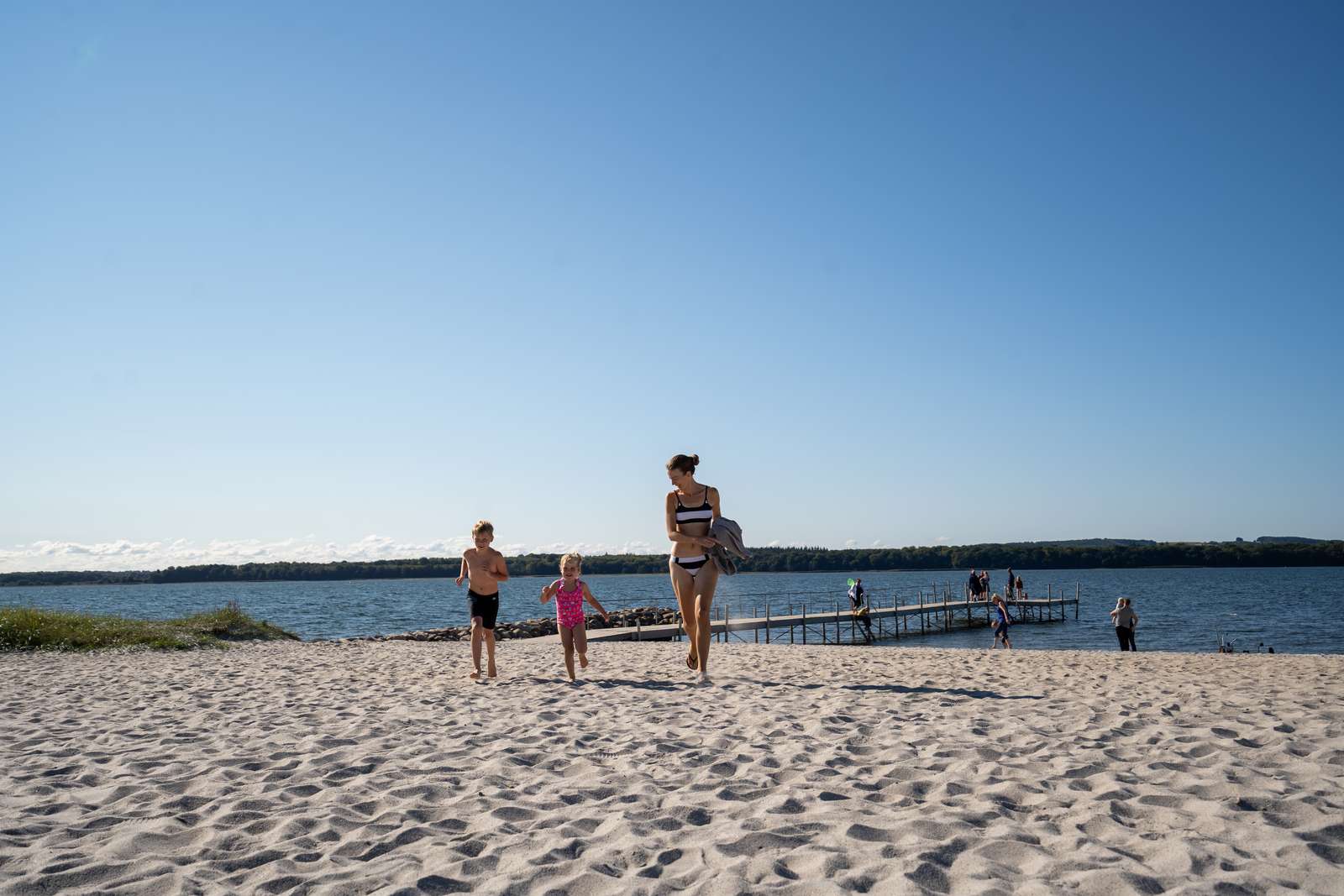 Mor og to børn går på Husodde Strand