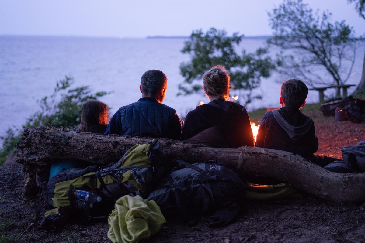 Familie sidder ved et bål i Staksrode Skov med udsigt over havet