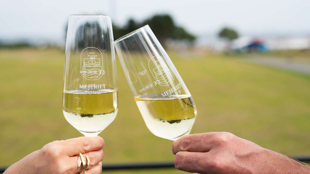 To hænder skåler med glas med logoet fra Mejeriet Tunø