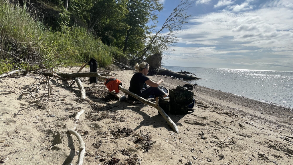 Helene Fruelund sidder på stranden ved sin rygsæk