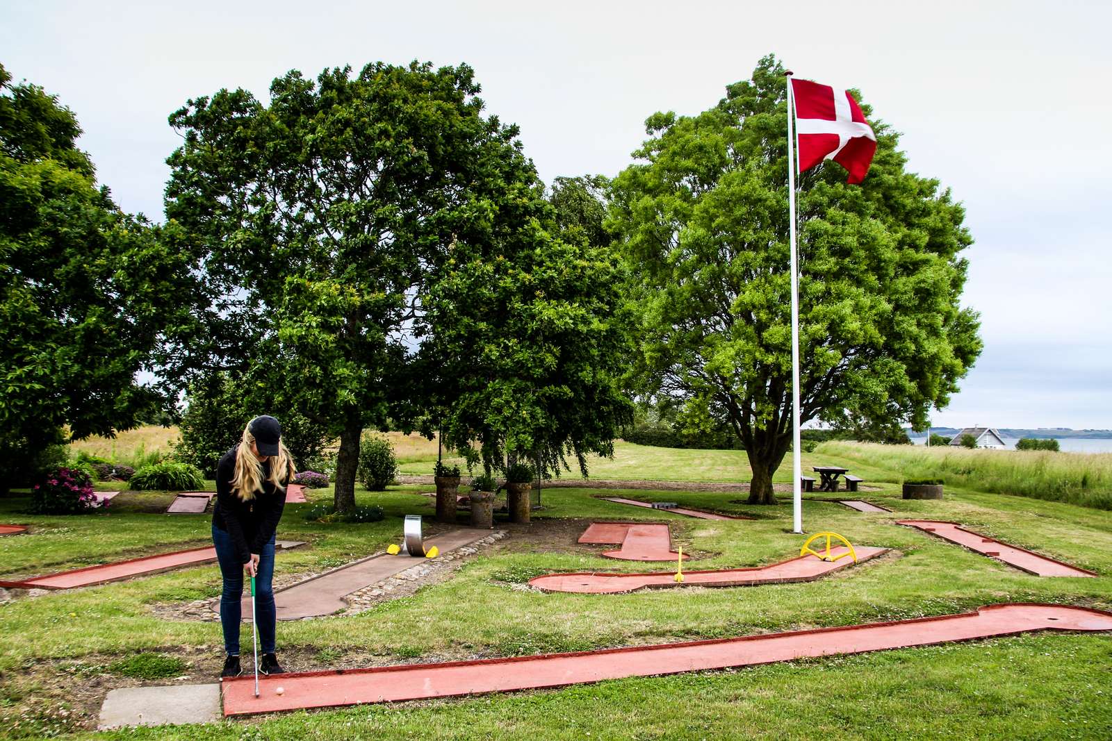 Kvinde slår til bolden på minigolfbanen hos Stalden Tunø Minigolf