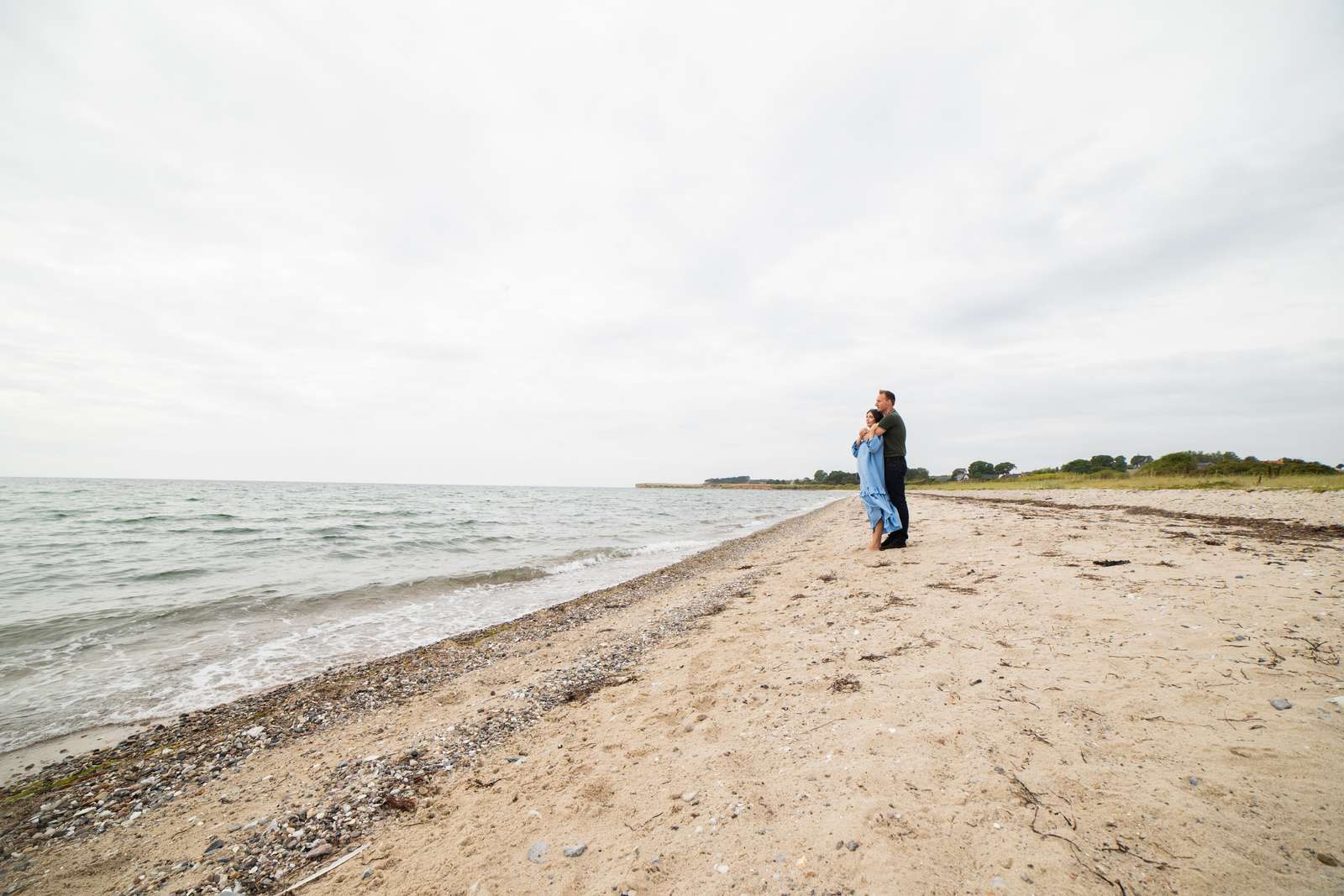 Et par omfavner hinanden på Tunø Nordstrand, mens de kigger ud på havet