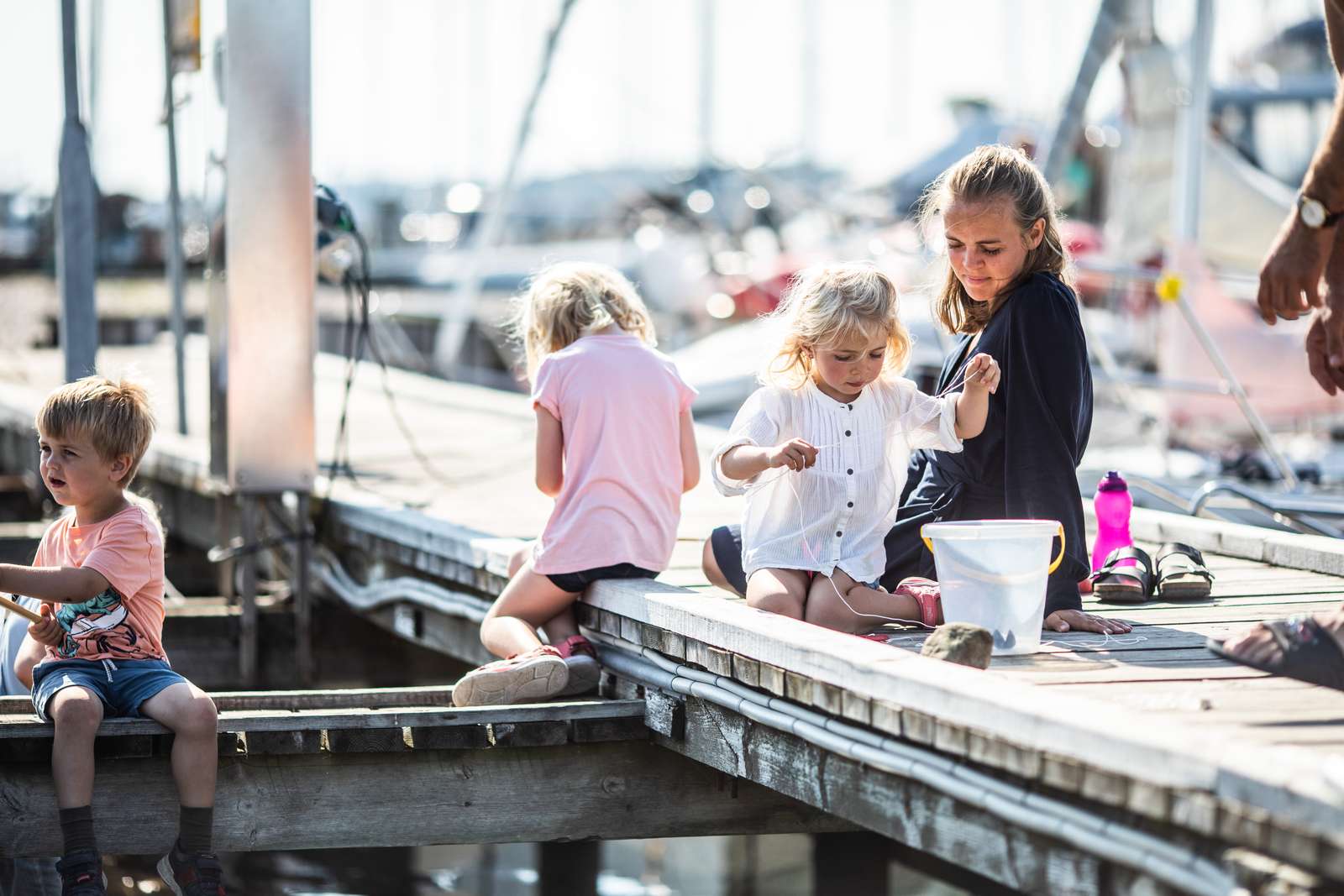 Familie med tre små børn fisker efter krabber fra krabbebroen på Norsminde Havn