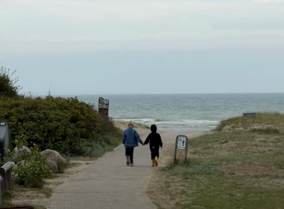 To børn går hånd i hånd ned til strand