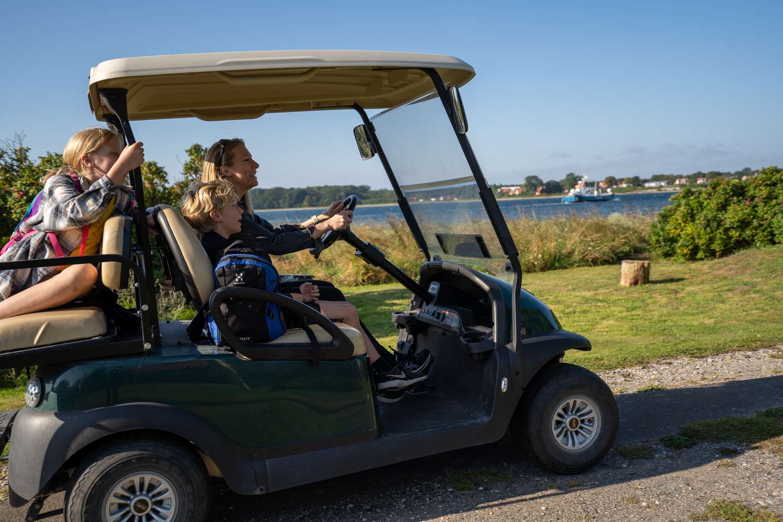 Familie sidder i en golfbil ved kysten på Hjarnø