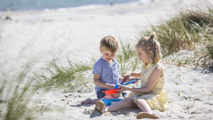 Children playing on the white sandy beach in Saksild