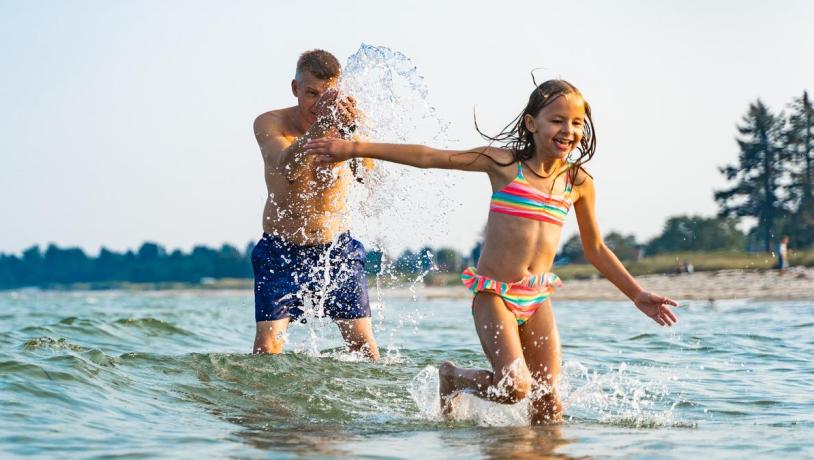 Father and daughter playing in the water at Saksild Beach in the Coastal Land