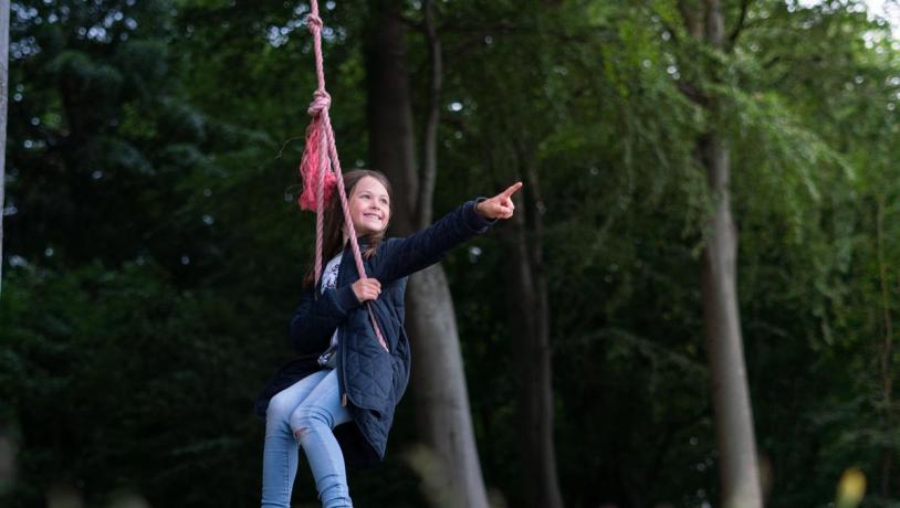 Girl swinging in a rope swing and pointing