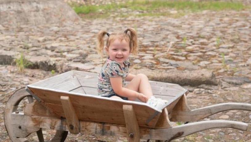 Cobblestones in courtyard with a child in a wheelbarrow and the white courtyard in background