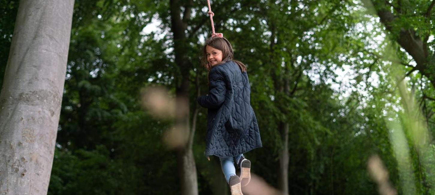 Girl swinging in a robe in a forrest in the coastal land