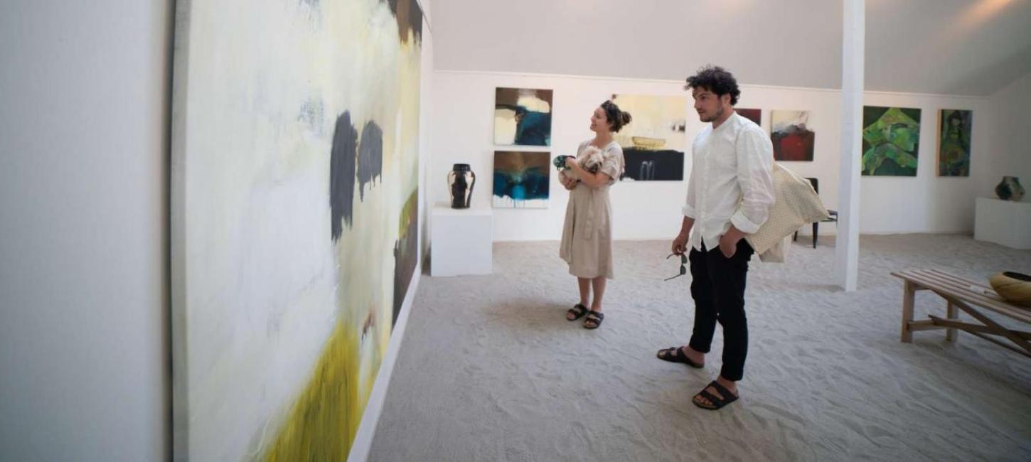 En kvinde og en mand nyder kunsten på Galleri Kirkesvinget på Hjarnø i Destination Kystlandet