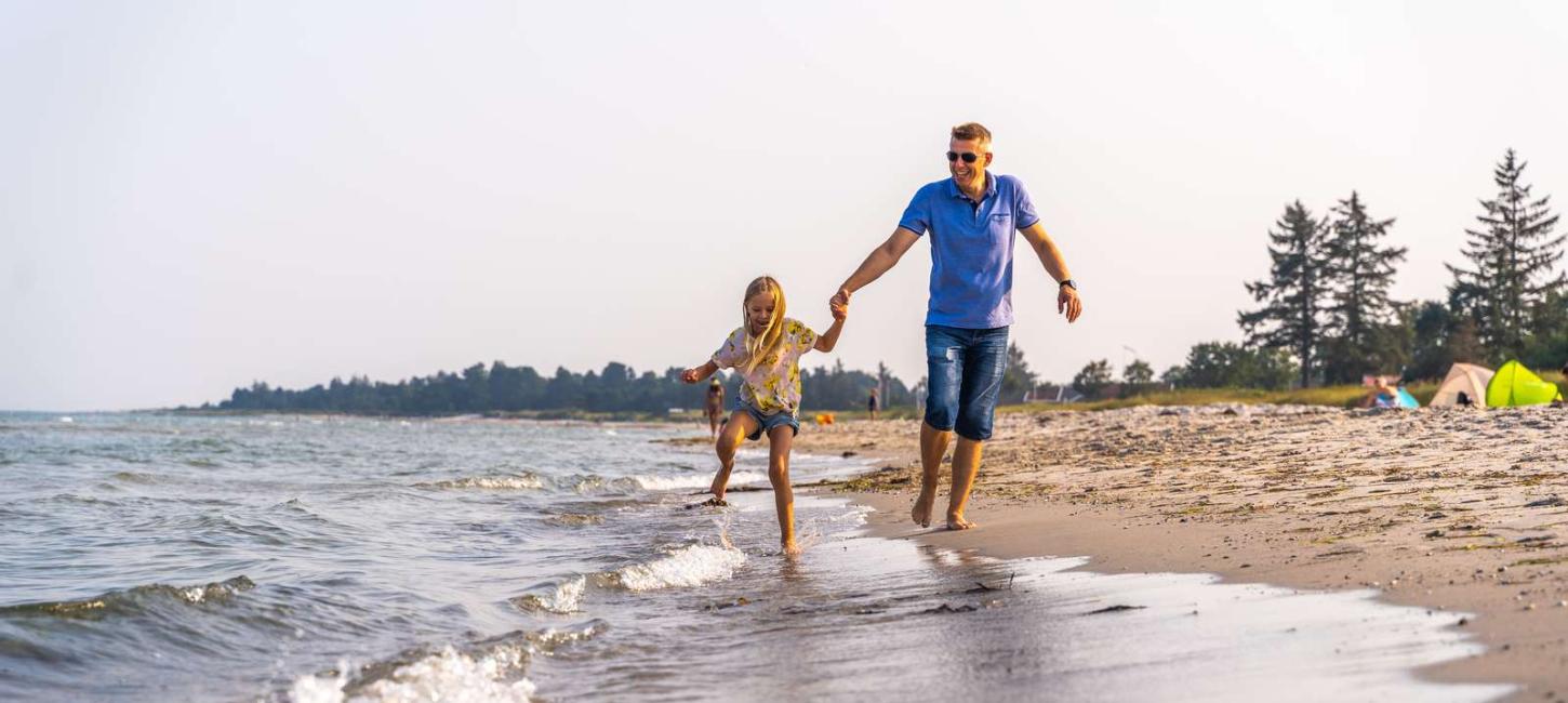 Father and daughter on the water's edge at Saksild Beach