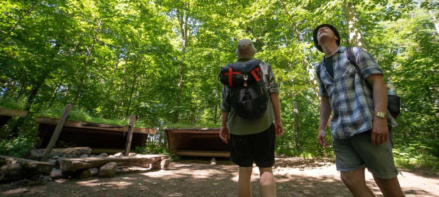 Two men on a hike at a shelter site in the forest