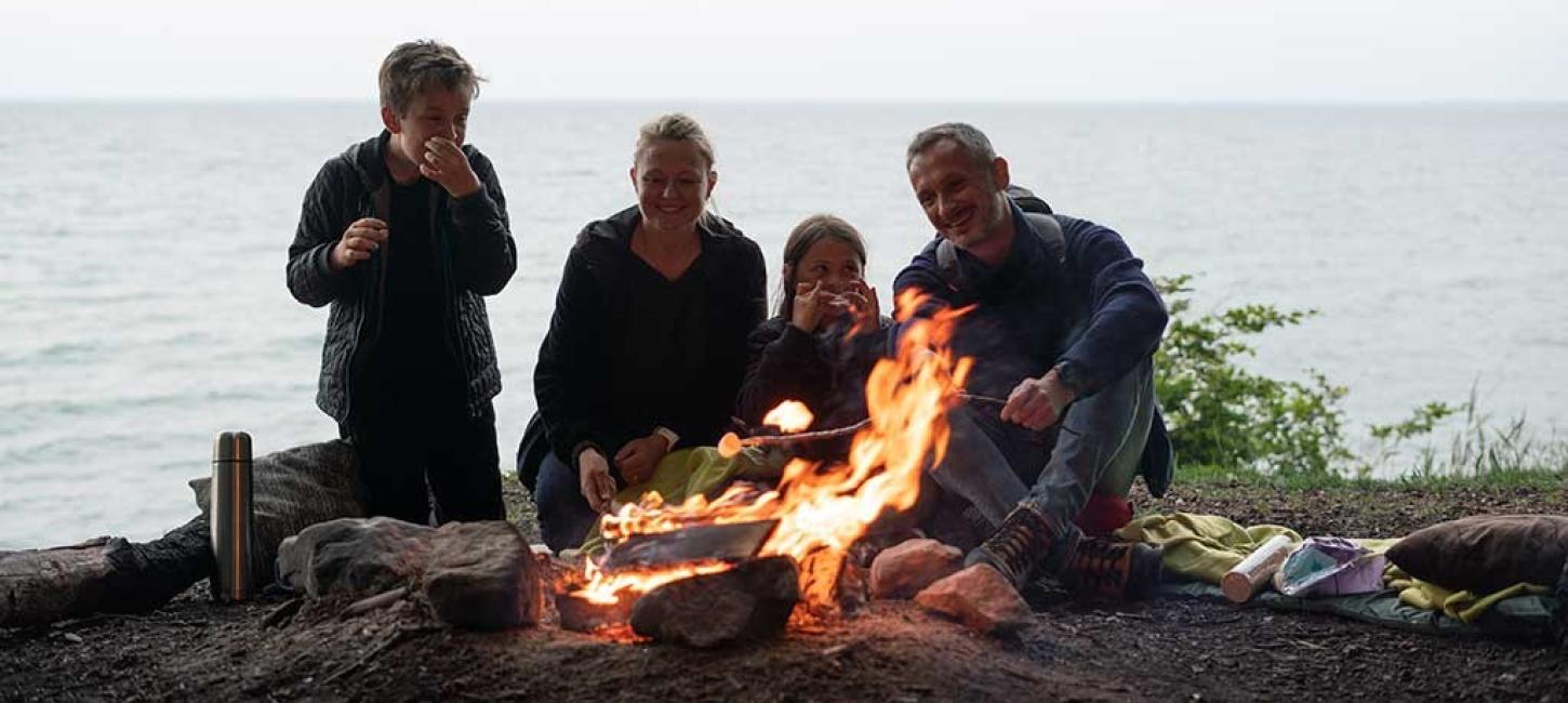 Family sitting around a campfire with sea views at Staksrode Forest