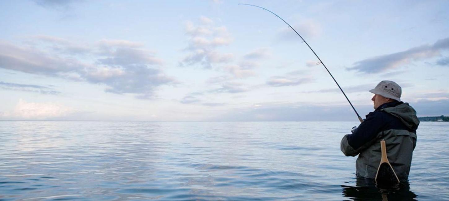 Man fishing in the sea at sunset