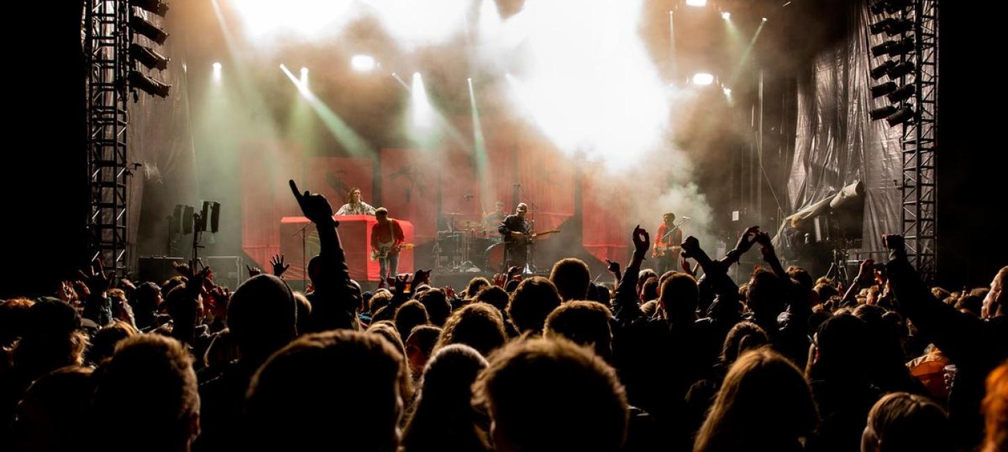 Hands in the air in front of a stage in the evening at the wall of sound in Destination Coastal Land