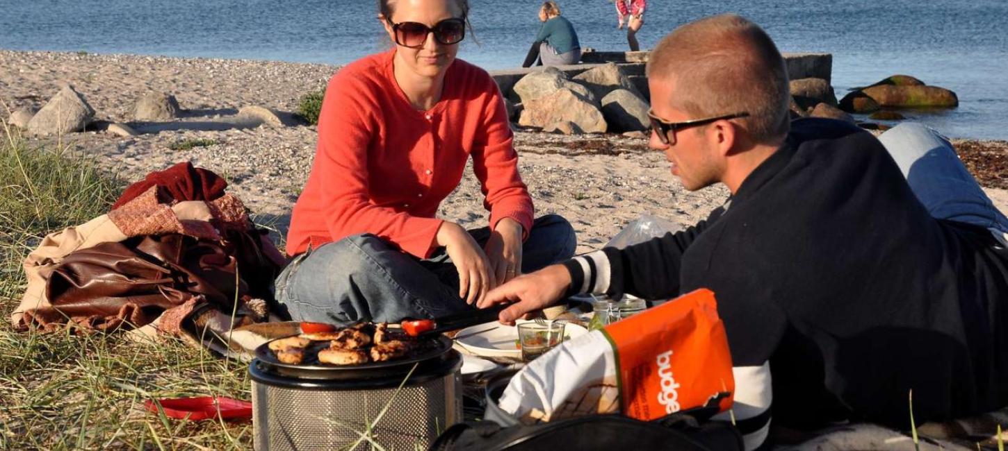 Family having fun and barbecuing by the beach at Ajstrup Camping - part of Destination Coastal Land