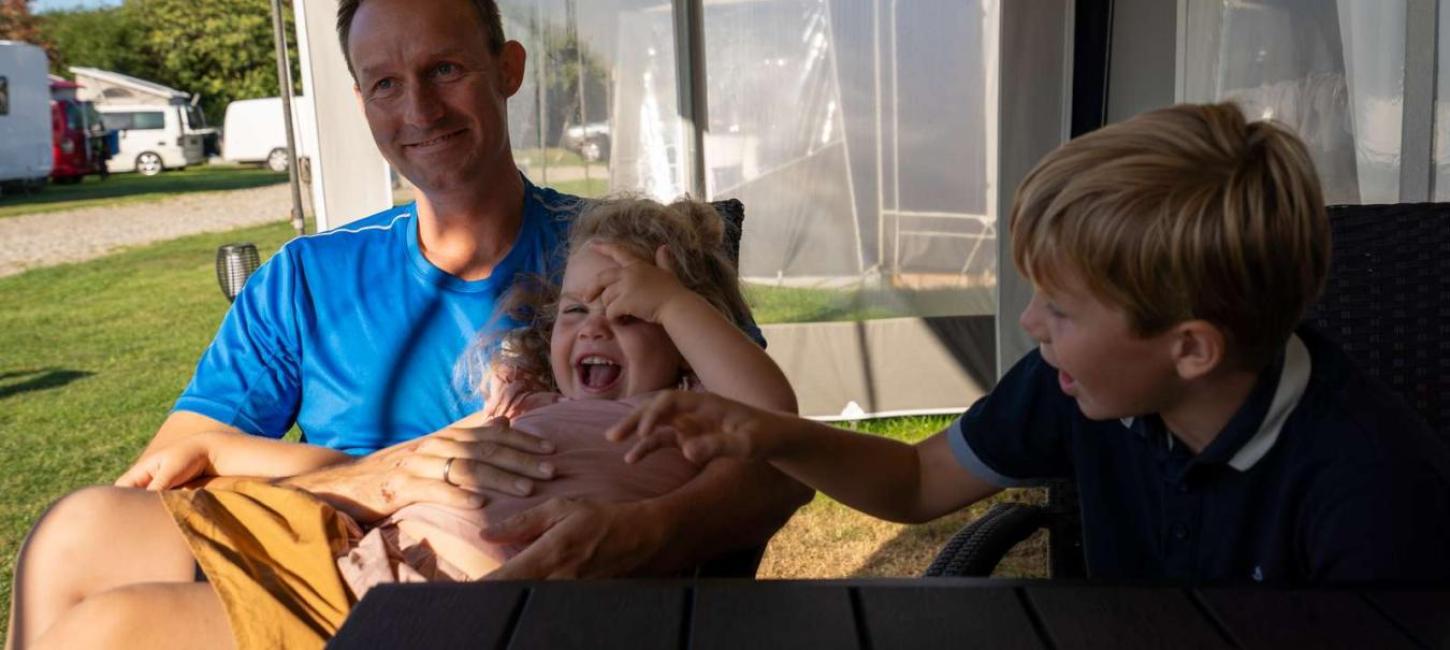 Father with two children in an awning by a caravan at Horsens City Camping - part of Destination Coastal Land