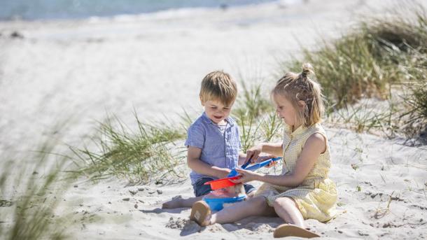 Children playing on the white sandy beach in Saksild