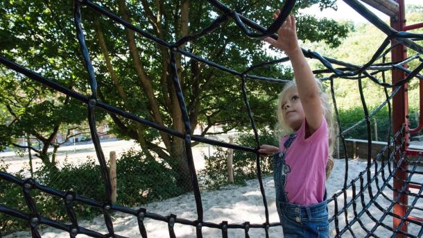 Girl crawling in the net on the playground in Bygholm Park