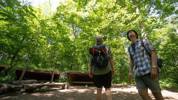 Two men on a hike at a shelter site in the forest