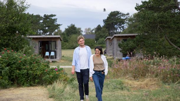 Couple waling towards the beach in front om cabin at Tunø Campsite in the Coastal Land in Denmark