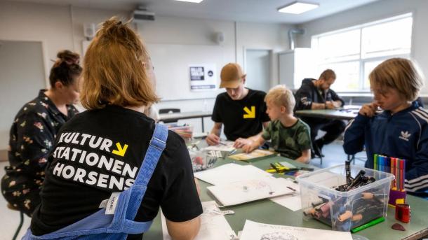 Children and families sitting at a table and drawing at the Culture Station (Kulturstationen) in Horsens, Destination Coastal Land