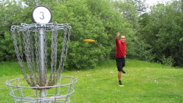 Mand spiller disc-golf med frisbee i park 