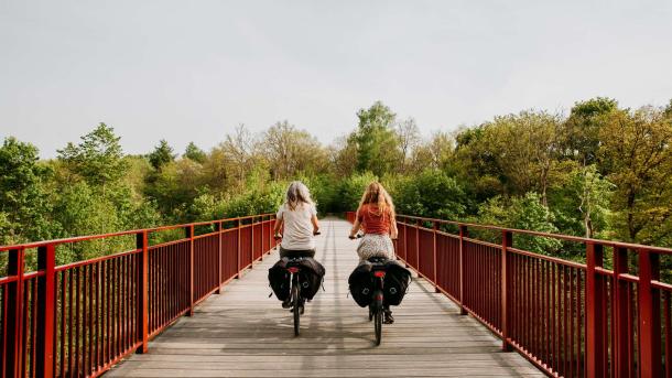 Kvinder cykler på elcykler på Den Genfundne Bro