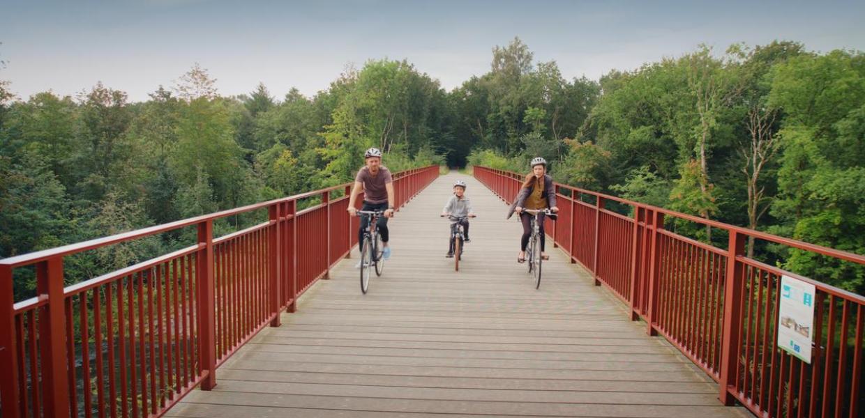 Family rides on their bikes on The Uncovered Bridge