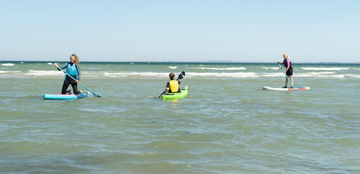 Women on SUP-boards and a man in a sea kayak at Saksild Beach