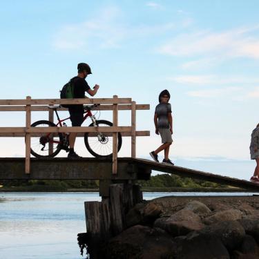 A man on a bicycle and two children on a bridge on Hjarnø