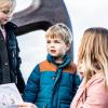 Mother and two children looking at treasure maps in front of the anchor in Juelsminde