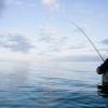 Man fishing in the sea at sunset