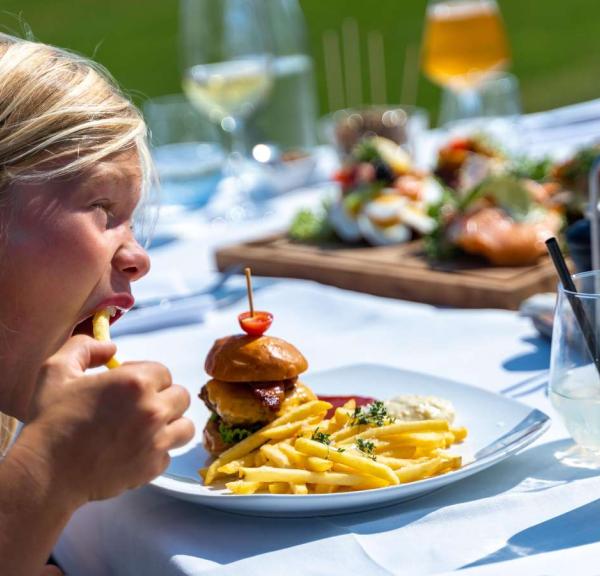 Boy eating a burger and French fries at the Dairy on Tunø, which is in Destination Coastal Land